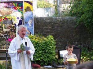 Vicar with rosemary, and helper with bowl of water.