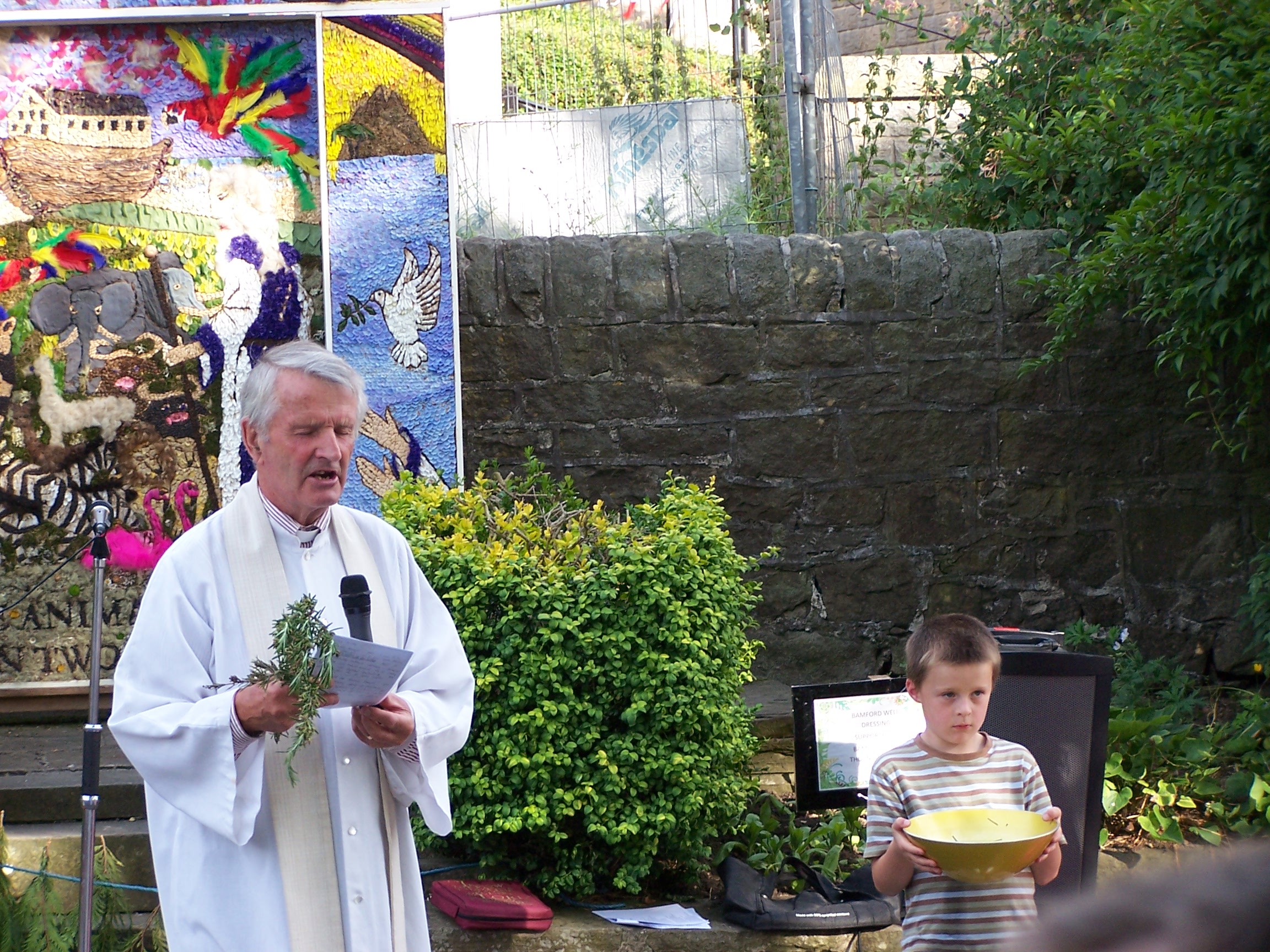 Vicar with rosemary, and helper with bowl of water.